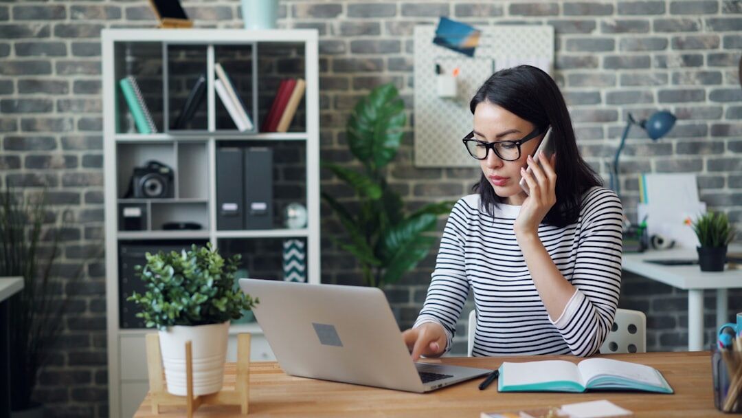 Person at desk using phone and laptop for communication